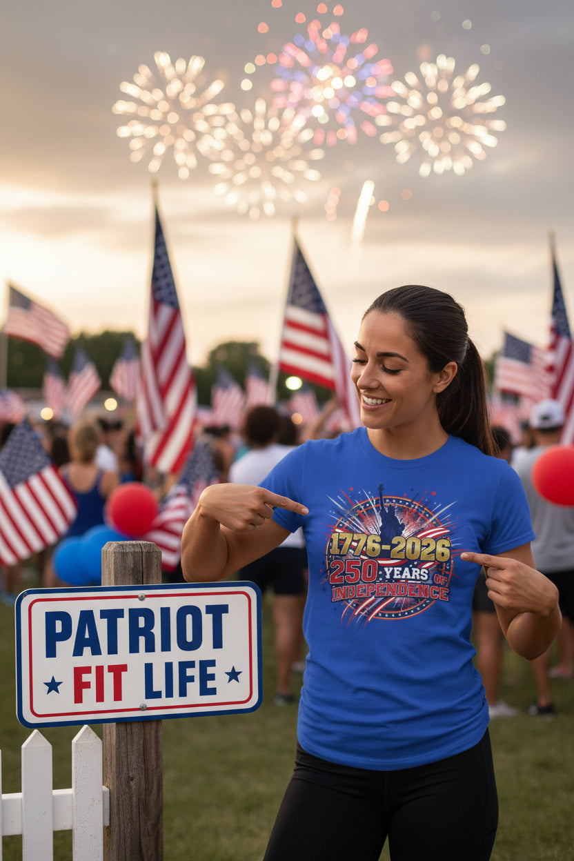 A woman in a 1776-2026 250 Years Of Independence blue t-shirt with a patriotic design at a 4th of July celebration with fireworks and American flags.