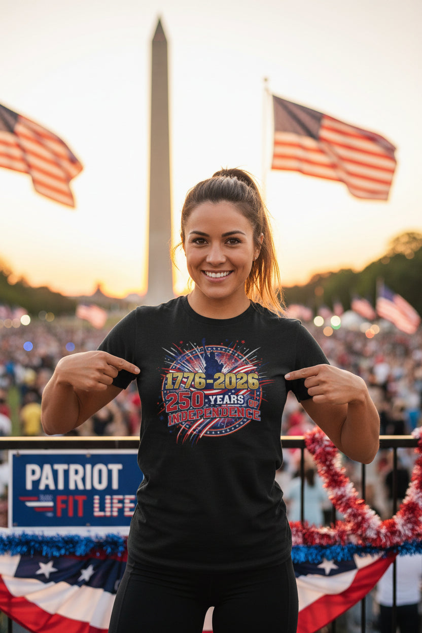 A woman wearing a 1776-2026 250 Years Of Independence black t-shirt with a patriotic design in front of American flags and the Washington Monument.